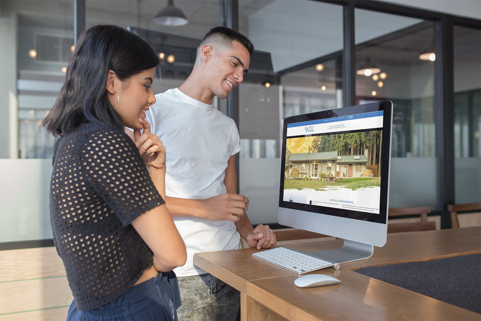 Reviewing a WordPress website creation project by Christine Abela Man and woman standing by an iMac in a modern office, reviewing the Central Otago Painters WordPress website built by Christine Abela.